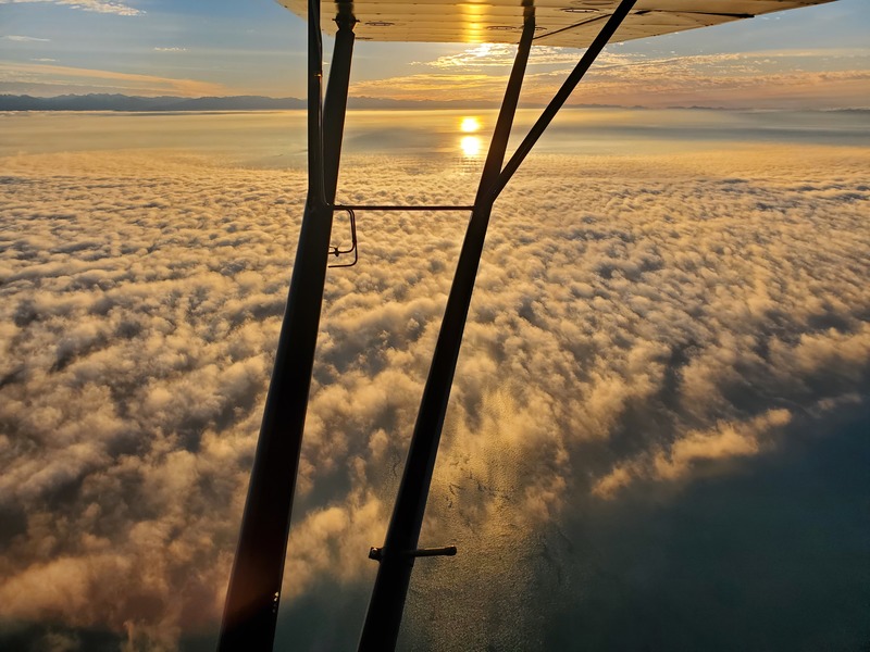 Photo of the sun just off the
wing, reflecting off the water, with rippled fog over the water